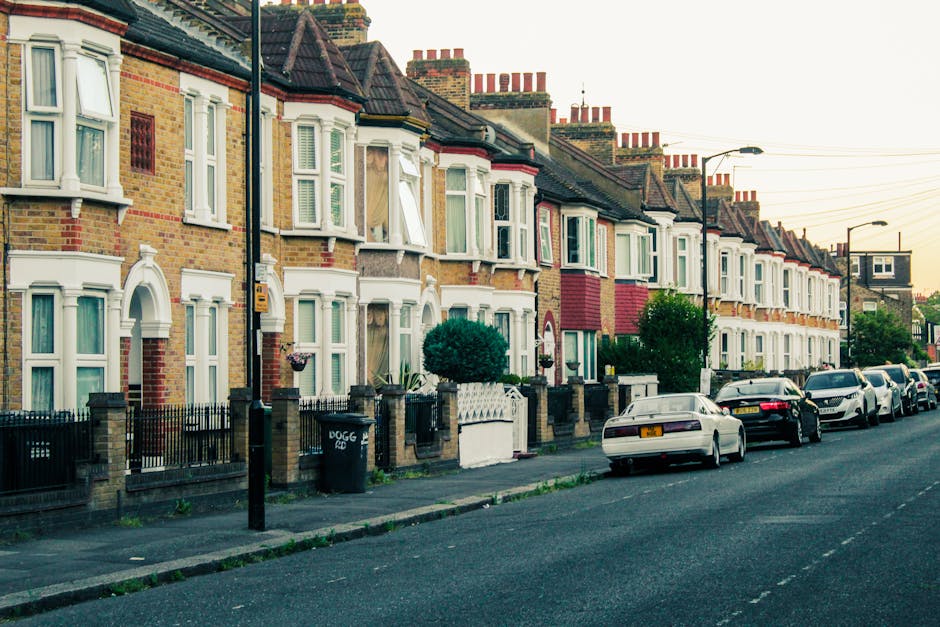 A row of traditional terraced residential houses on Victoria Road with brick facades, some featuring decorative white window trims and bay windows, many with pitched dark tiled roofs and numerous bric